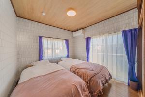two beds in a room with a window at Third Place Villa KISARAZU in Kisarazu