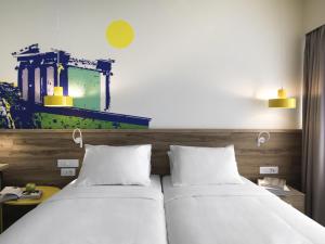 two beds in a hotel room with white sheets at ibis Styles Athens Routes in Athens