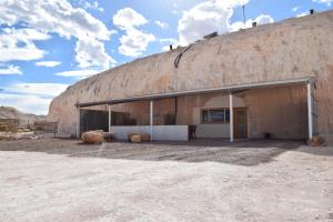 
a large white building with a black roof at Dug Out B&B Apartments in Coober Pedy
