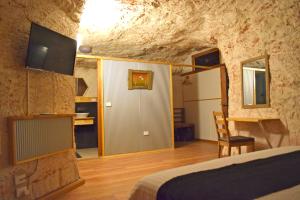 a bedroom in a cave with a bed and a desk at Dug Out B&B in Coober Pedy