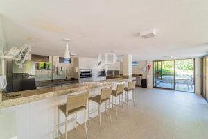a kitchen with a bar with stools in it at Apartamento a beira-mar com piscina in Cabedelo