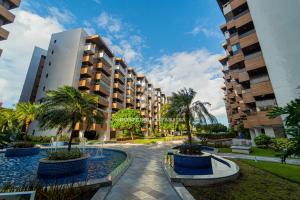 a courtyard with palm trees and buildings at Apartamento a beira-mar com piscina in Cabedelo