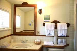 a bathroom with a sink and a mirror and towels at La Remontée Appartements Hôtel in La Malbaie +30 photos