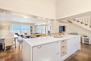 a kitchen with a white island and a living room at Sea Haven 4 in Gordonʼs Bay