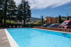 a large blue swimming pool in a yard with parked cars at Casa Anna in Paratico