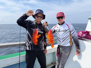 two men standing on a boat holding fishing rods at ハーミットクラブ in Goto