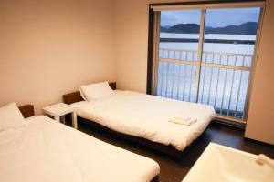 two beds in a room with a window and a sink at ハーミットクラブ in Goto