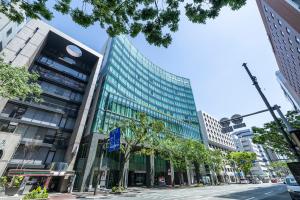 a tall glass building on a city street at KOKO HOTEL Premier Hakata in Fukuoka