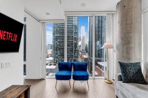 a living room with blue chairs in front of a large window at Altitude Residences in Toronto