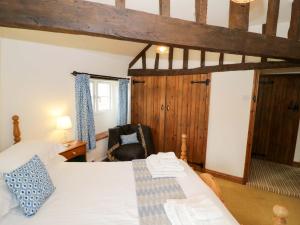 a bedroom with a bed and a chair in a room at Elmhurst Cottage in Quinton
