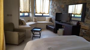 Habitación con cama, TV y sofá. en Sea Sight Boutique Hotel en Pórto Ráfti