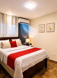 a bedroom with a large bed with a red blanket at spring house jarabacoa bbq ,piscina privada, Wi-Fi deco 10 huéspedes 3 baños, 2 aires A C 4 habitaciones in Jarabacoa +36 photos