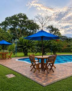 a table and chairs with an umbrella next to a pool at Hotel Boutique Casa Bonanza in Guamal