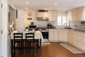 a kitchen with white cabinets and a kitchen island with stools at Cozy Coastal Retreat Close to Beach Park in Port Moody