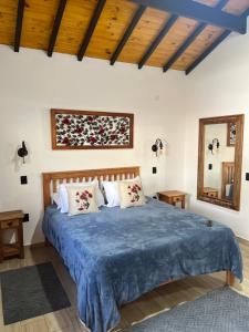 a bedroom with a large bed with a blue blanket at Chalé Vila do Aeroporto in Monte Verde