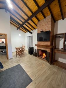 a living room with a fireplace and a tv at Chalé Vila do Aeroporto in Monte Verde