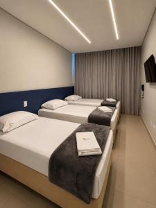 a room with three beds in a room at Hotel Salute Brasília l SLEEP HOTÉIS in Taguatinga