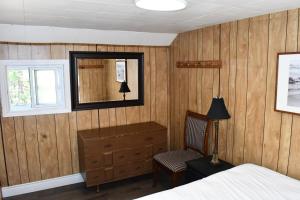 a bedroom with a bed and a mirror and a chair at Private Beach Access -Cottage 15 in Sauble Beach +8 photos