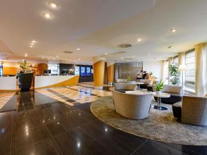 a lobby with chairs and tables in a building at Mövenpick Hotel Egerkingen in Egerkingen
