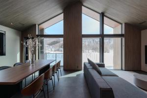 a dining room with a table and chairs and large windows at Forest Resort Walnut in Hakuba