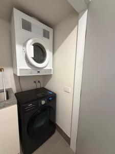 a kitchen with a washing machine and a microwave at Stylish CBD Apartment with Courtyard and Parking in Newcastle +21 photos