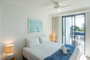 a white bedroom with a bed and a large window at Swell Resort Burleigh Heads in Gold Coast +38 photos