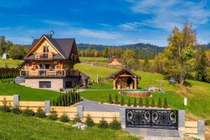 a large house in a green field with a fence at Luxury holiday villa, pool, sauna, jacuzzi in Nowy Targ