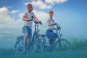 a man and a woman riding bikes in a field at Lakeside holiday villa, private garden in Wierzchowo