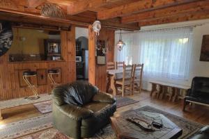 a living room with a leather chair and a table at Lakeside holiday villa, private garden in Wierzchowo