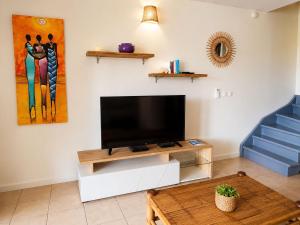 a living room with a flat screen tv on a white cabinet at VILLA CARAIBE in Sainte-Luce