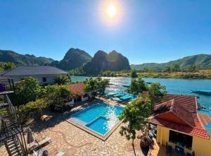 an aerial view of a resort with a river and mountains at Jade River Phong Nha in Phong Nha