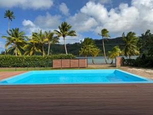 a blue swimming pool with a bench and the ocean at Villa Blue Lagoon Tahaa in Tahaa