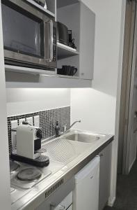 a kitchen with a sink and a microwave at Art Deco Chic on Queen in Auckland