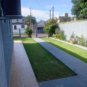 a garden with a sidewalk next to a grassy yard at Suíte completa na Região do Lago in Cascavel