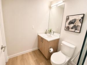 a bathroom with a toilet and a sink and a mirror at Lovely Brand New Condo in Sidney +10 photos