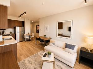 a living room with a white couch and a kitchen at Lovely Brand New Condo in Sidney