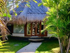 a house with a thatched roof and a pathway at Emocean Beach Boutique Dive Resort in Amed