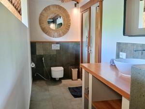 a bathroom with a sink and a mirror and a toilet at Emocean Beach Boutique Dive Resort in Amed