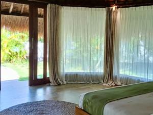 a bedroom with a bed and large windows at Emocean Beach Boutique Dive Resort in Amed