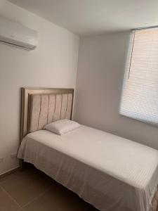 a bed in a white room with a white bedspread at El paraíso in Gaira