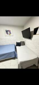 a bedroom with two beds and a flat screen tv at Hostal CAMPOAMOR in Medellín