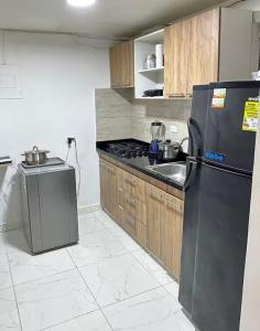 a kitchen with a black refrigerator and a sink at Hostal CAMPOAMOR in Medellín