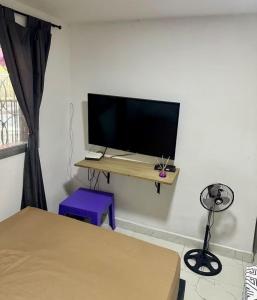 a room with a television on a table with a bed at Hostal CAMPOAMOR in Medellín +11 photos