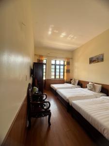 a room with two beds and a chair in it at TINH DOI SA PA Guest House in Sapa