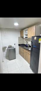 a kitchen with a black refrigerator and a sink at Hostal CAMPOAMOR in Medellín