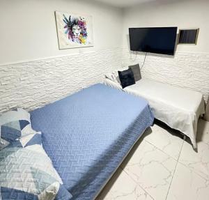 a bedroom with two beds and a flat screen tv at Hostal CAMPOAMOR in Medellín