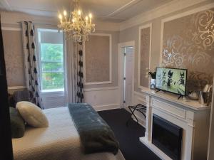 a bedroom with a bed with a fireplace and a chandelier at The Tamworth Hotel, Tamworth ,Ontario, Canada in Tamworth