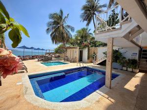 a swimming pool in front of a house with the ocean at Hotel Caribbean Cartagena in Cartagena de Indias