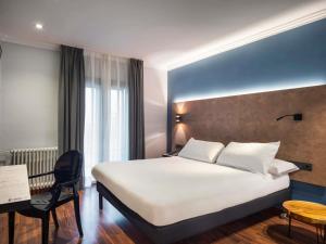 a hotel room with a white bed and a desk at Ibis Styles Figueres Ronda in Figueres