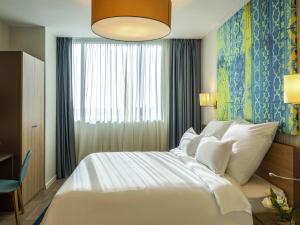 a bedroom with a white bed and a window at Adagio Jeddah City Center in Jeddah